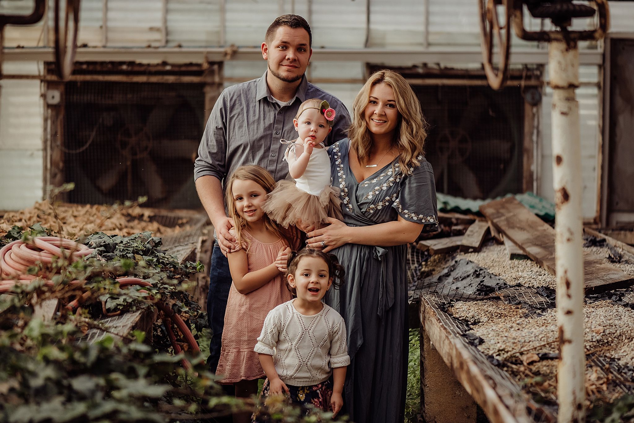 Family poses together in rustic outdoor garden setting during golden hour.