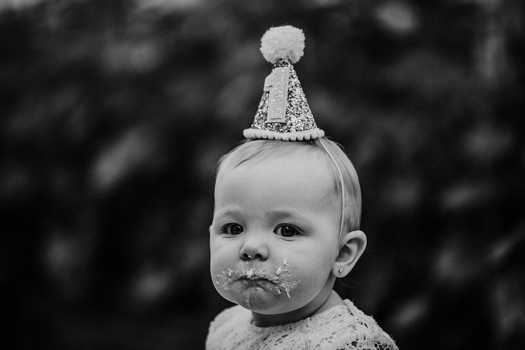 A small celebrant wearing a sparkly party hat in black and white portrait style.