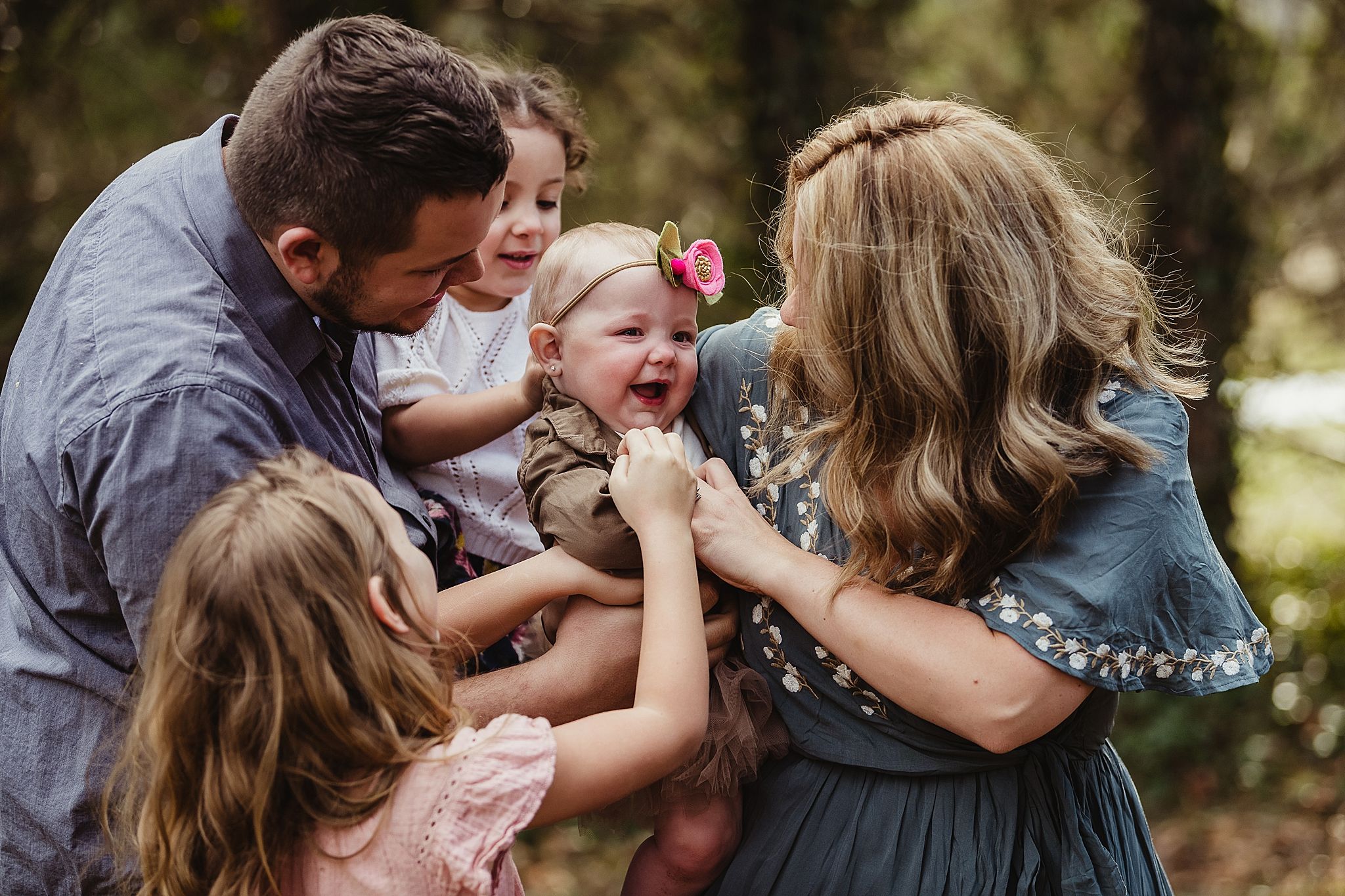 Joyful family sharing playful moment outdoors surrounded by greenery.