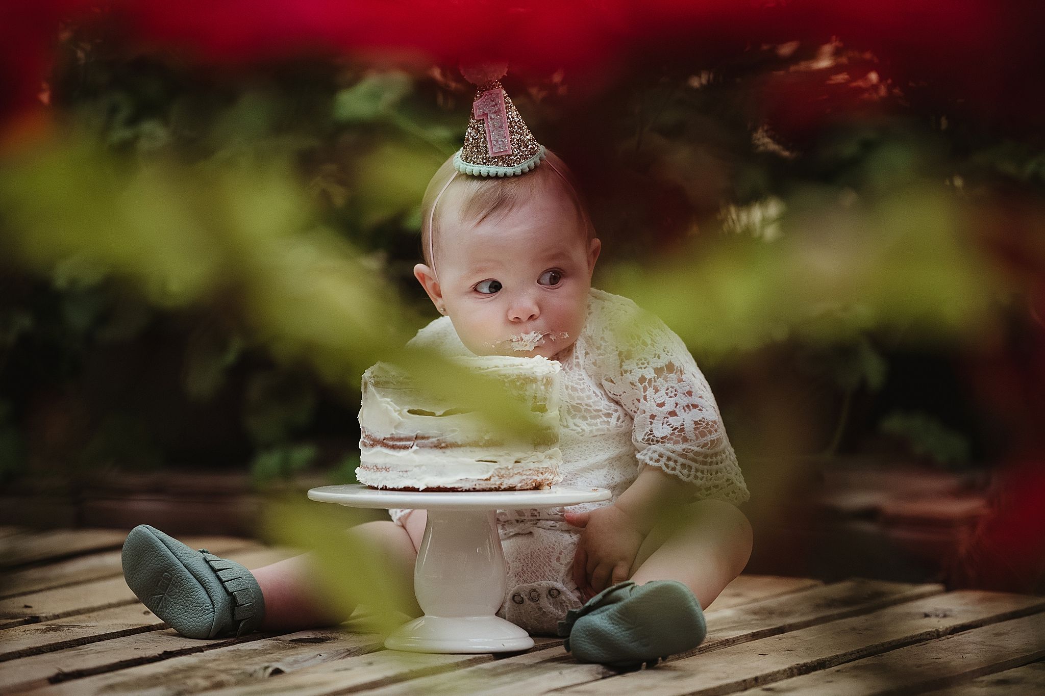 A festive moment captured through red foliage with a small cake on a wooden surface.