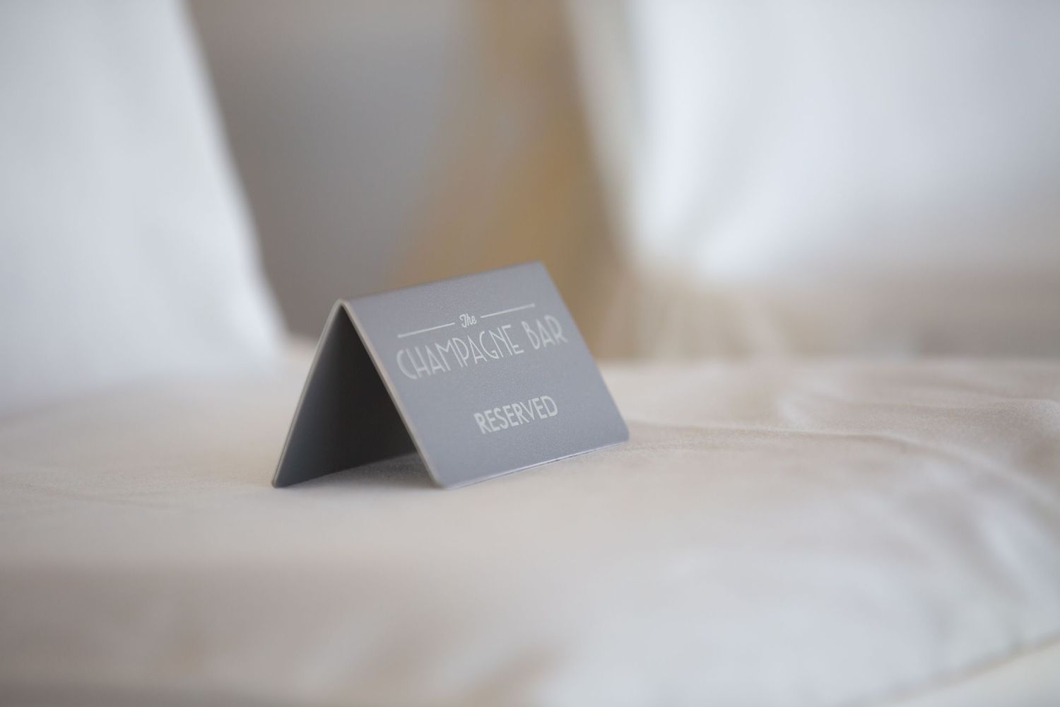 Close up of folded paper place card on white linen surface.