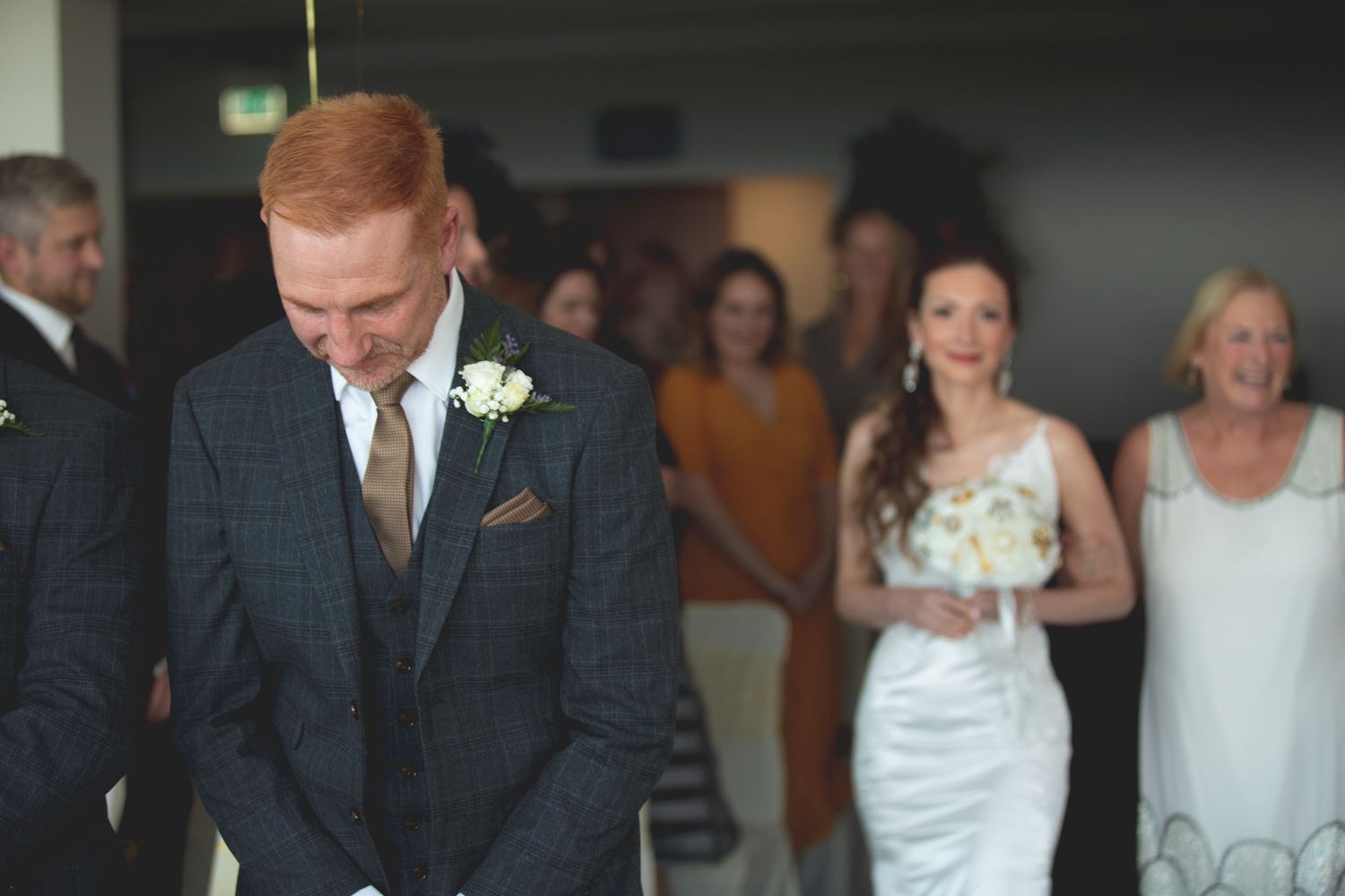 Wedding party members in formal attire walking through an indoor venue.