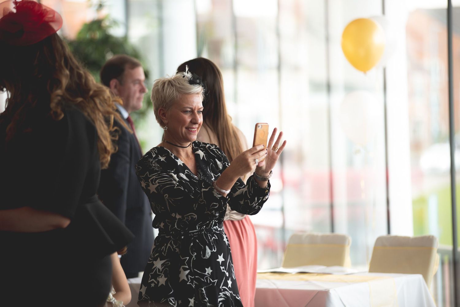 Event guests mingle and celebrate at an indoor gathering with decorative balloons.