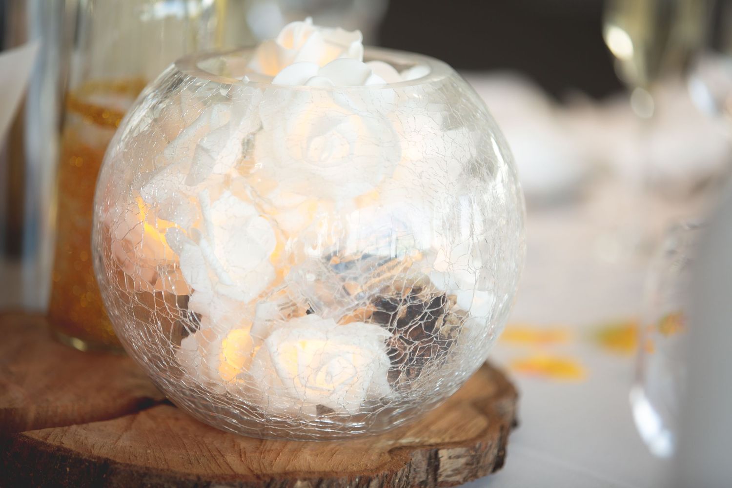 Glowing glass globe centerpiece on wooden base with candlelight effect.