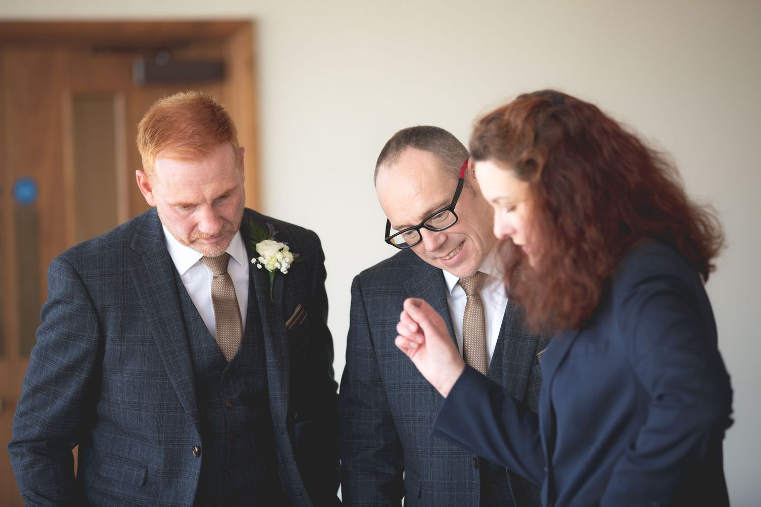 Three people in formal attire having an animated conversation at an indoor event.