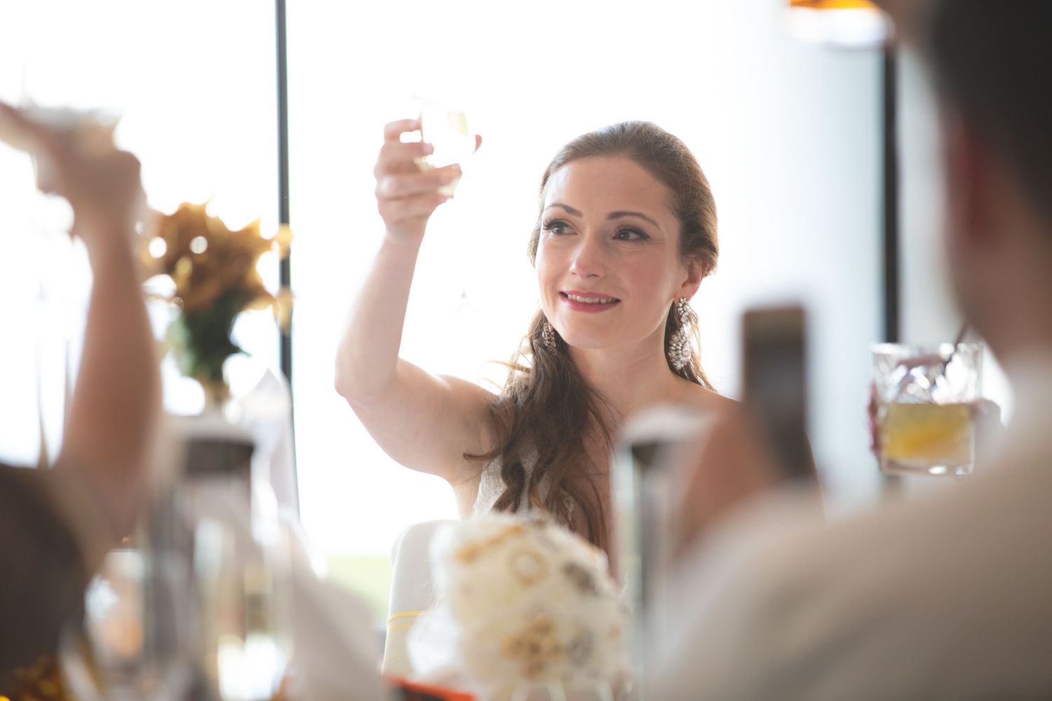 Guest raising glass for celebratory toast at formal wedding reception.