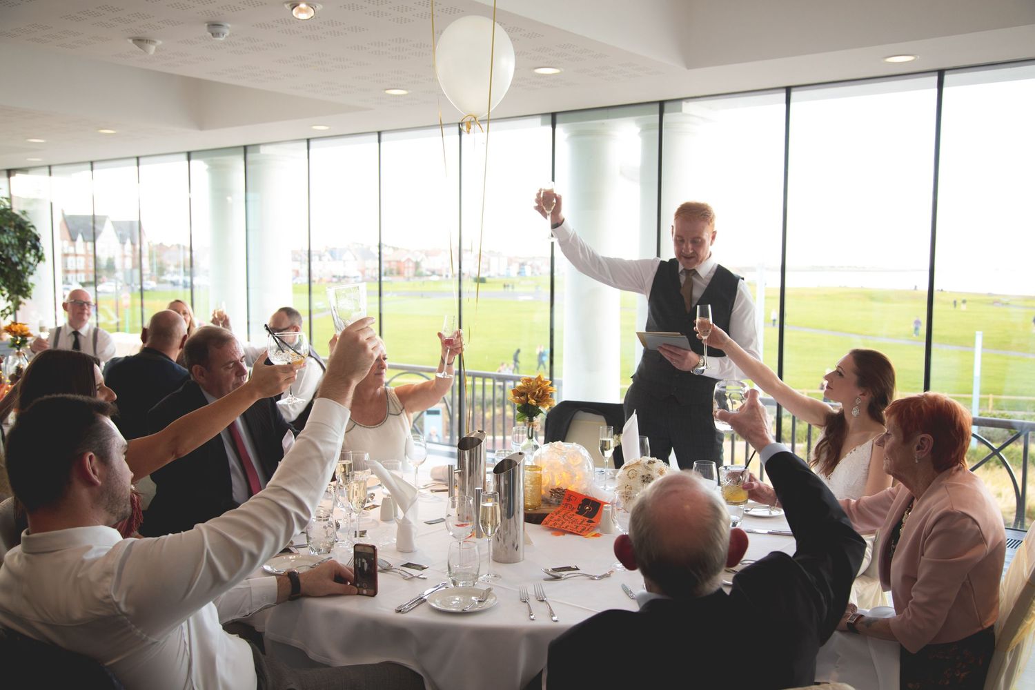Wedding guests raising glasses during celebratory toast at reception.