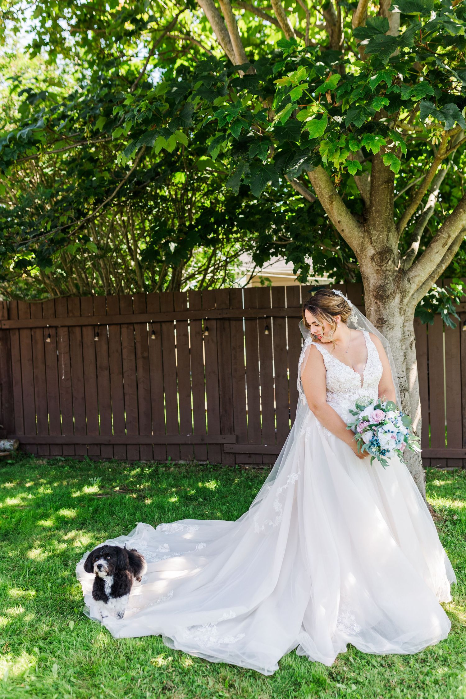 Wedding dress photoshoot in garden with black and white cat sitting on grass.