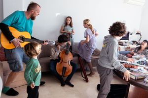 Family having fun with musical instruments in a casual living room gathering.