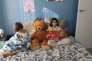 hermanos leyendo en la cama de sus padres