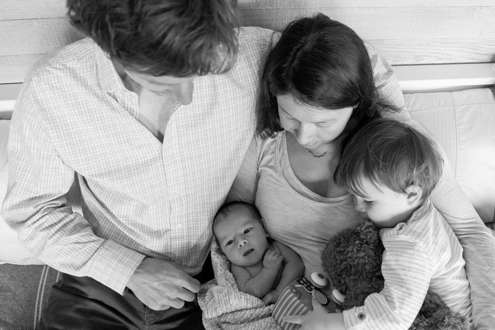 Black and white family photo showing tender moment with newborn.