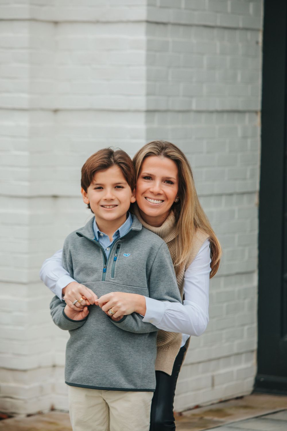Casual outdoor portrait session against a white brick wall background.