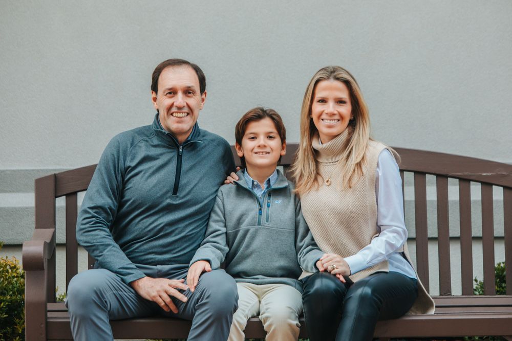 Family sitting together on a bench during an outdoor photo session.