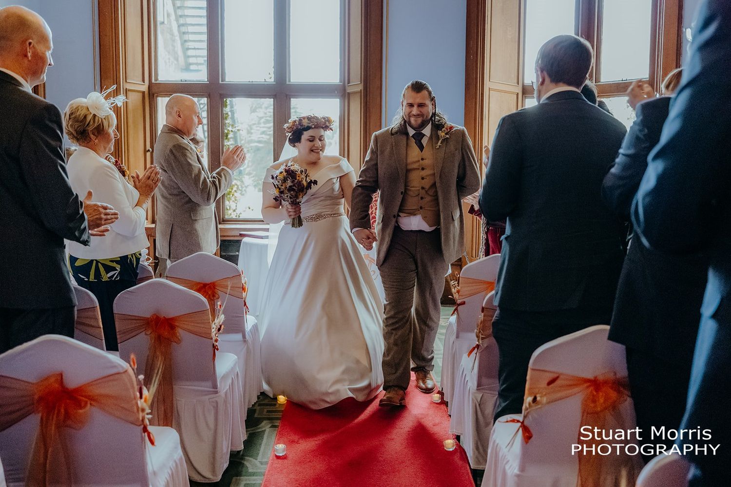 bride and groom hold hands walking up the aisle at Ruthin castle north Wales. Stuart Morris Photography