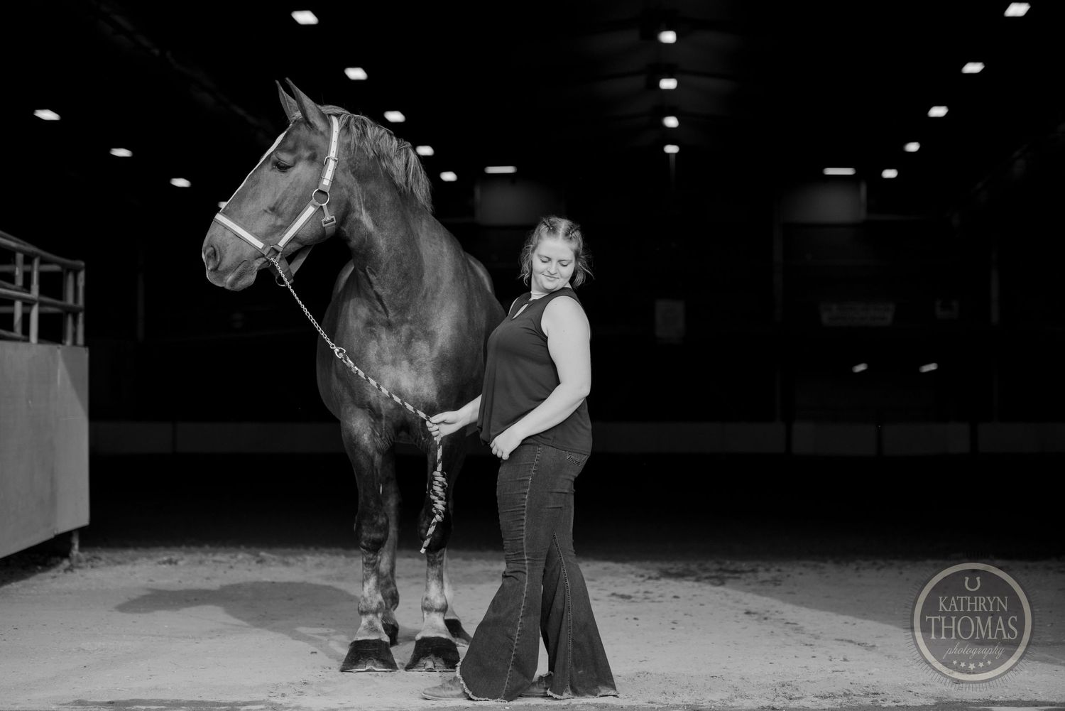 A monochrome photo captures a horse and handler posing together in an indoor arena setting.