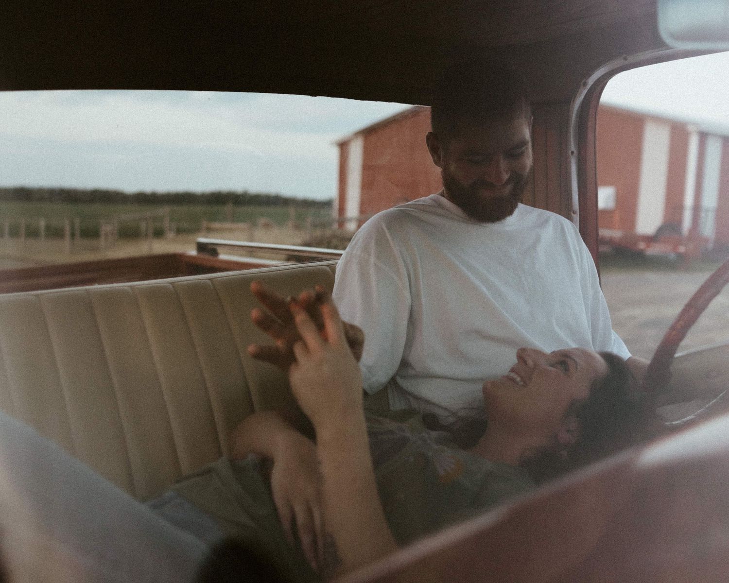 a couple smiling at each other in a vintage ford pick up truck