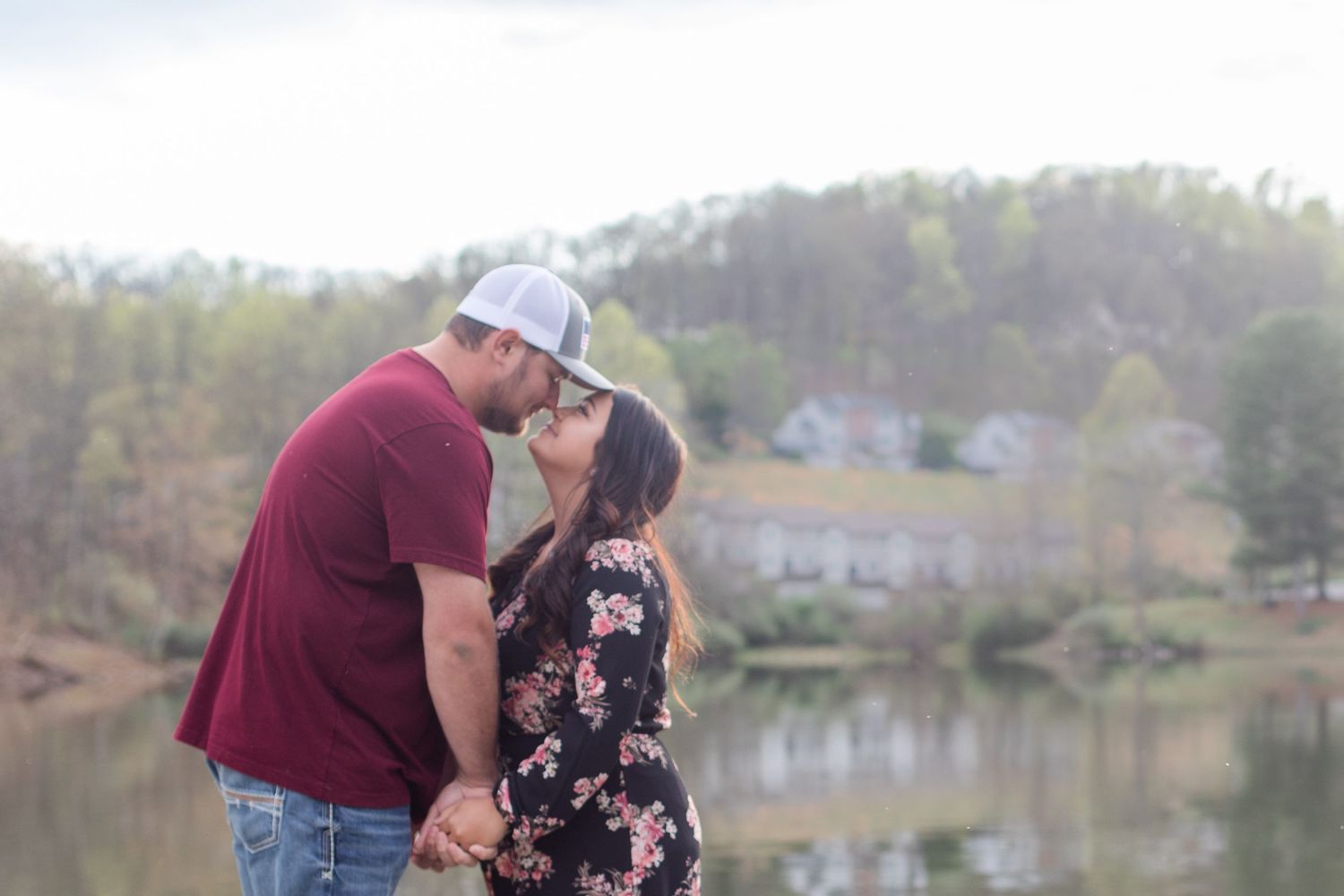 Couple shares romantic moment on dock overlooking peaceful lake surrounded by autumn trees.