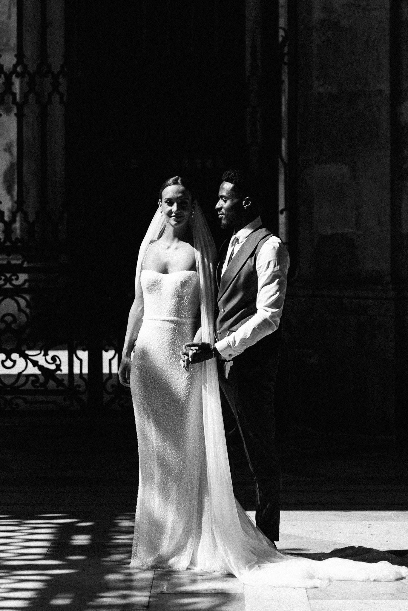 Black and white artistic wedding photo with dramatic lighting and shadows.