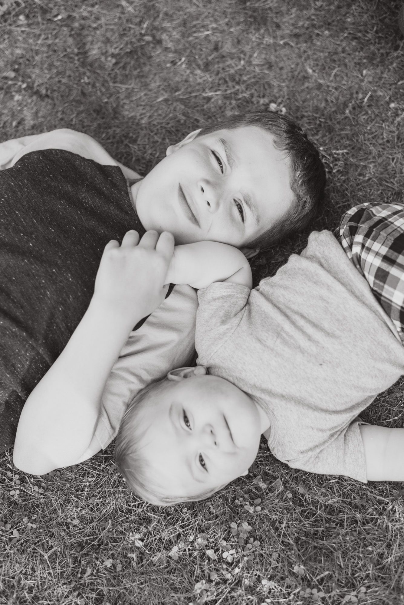Big brother and little brother laying in grass in black and white in Mars, Pennsylvania