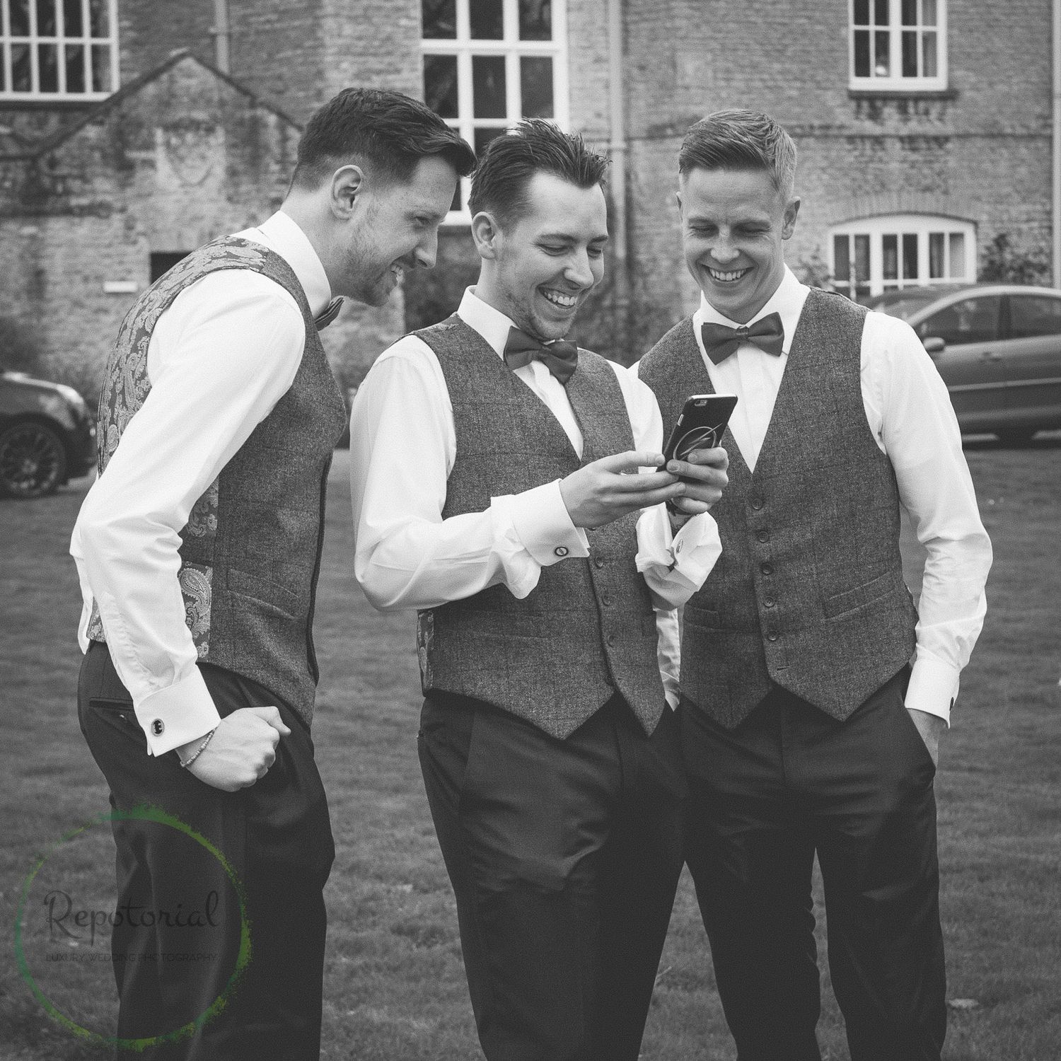 groomsmen laughing at something on mobile phone
