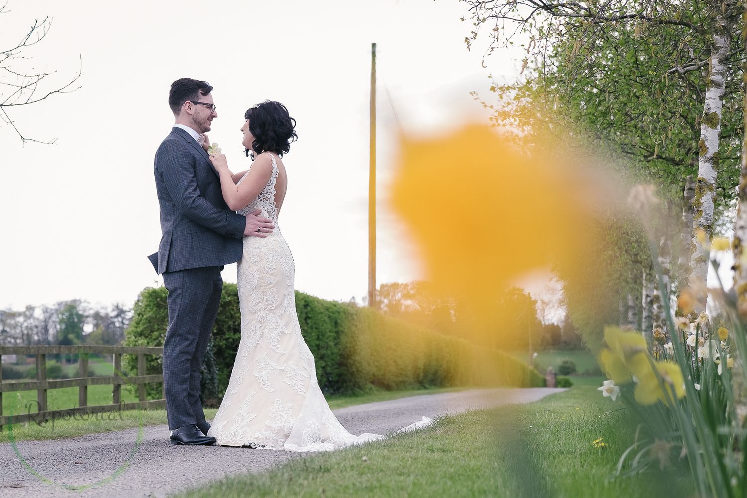 spring wedding portrait with out of focus daffodil and bride and groom looking at each other