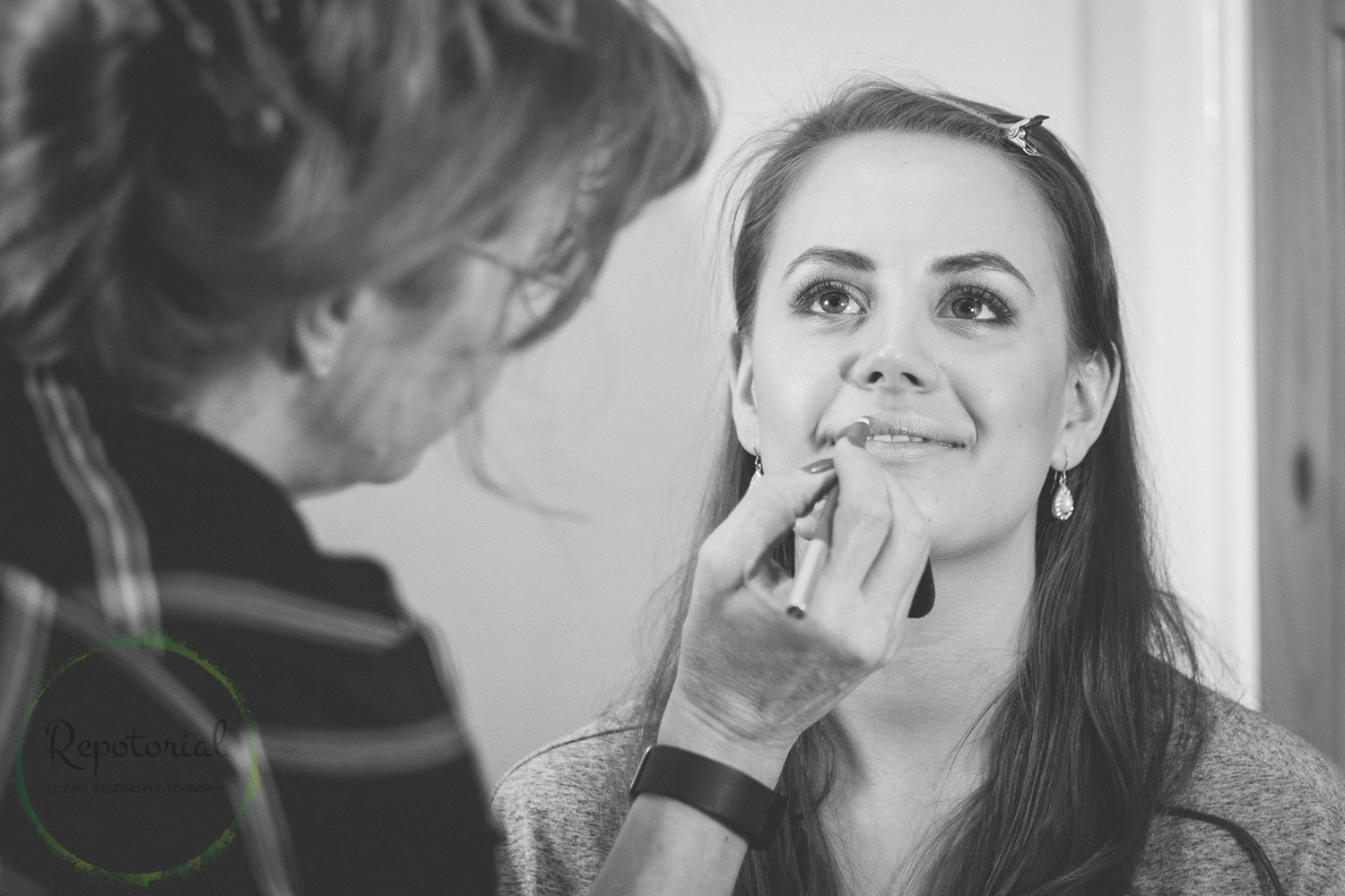monochrome photo of MUA make up artist applying make up to smiling bridesmaid