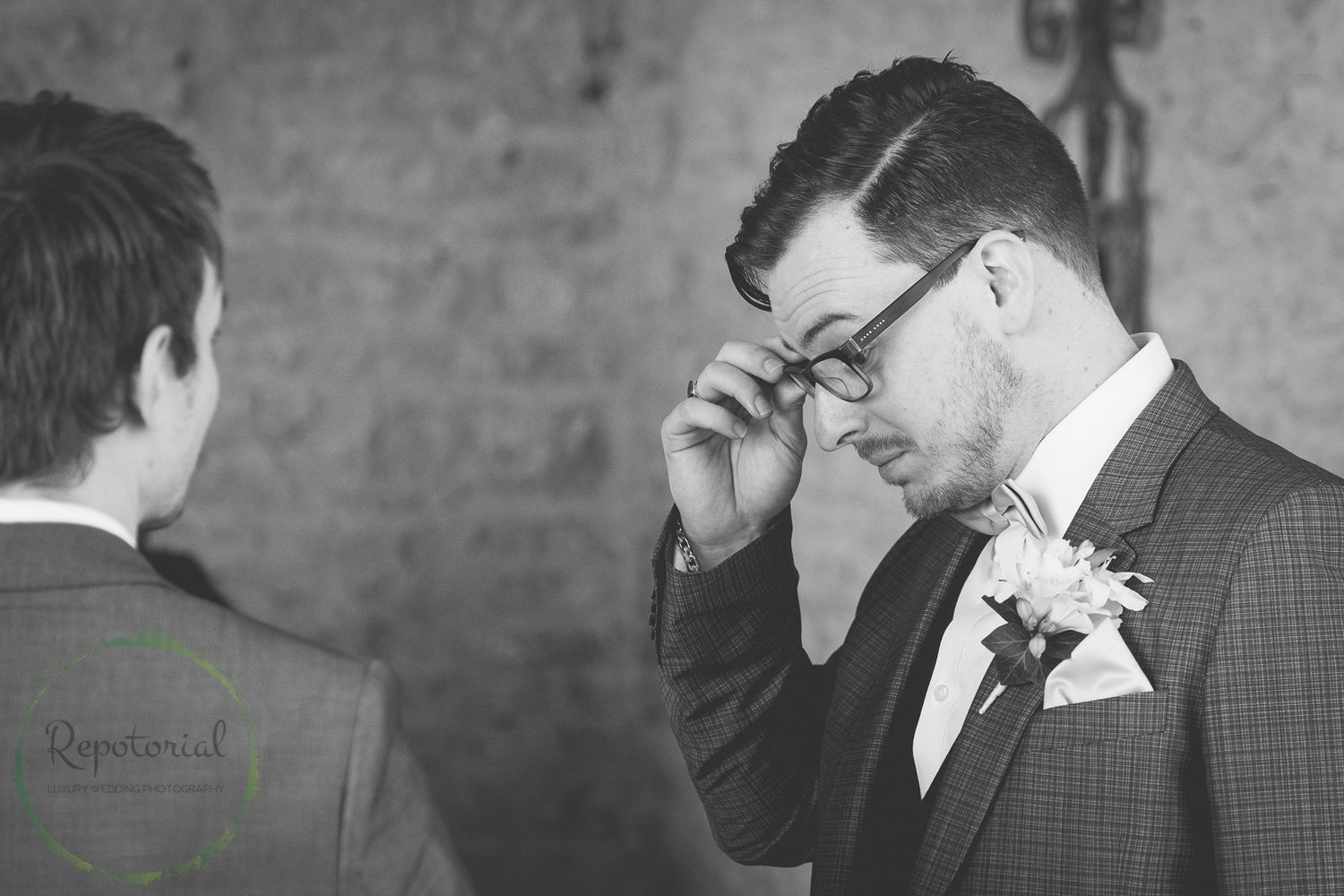 monochrome wedding image of groom adjusting glasses before wedding ceremony