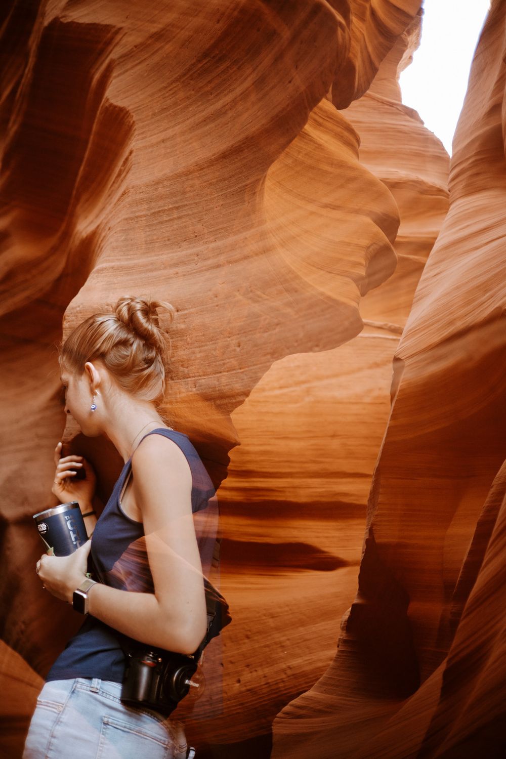 Woman holding a water bottle while walking through tunnels of Antelope Canyon in Page, Arizona