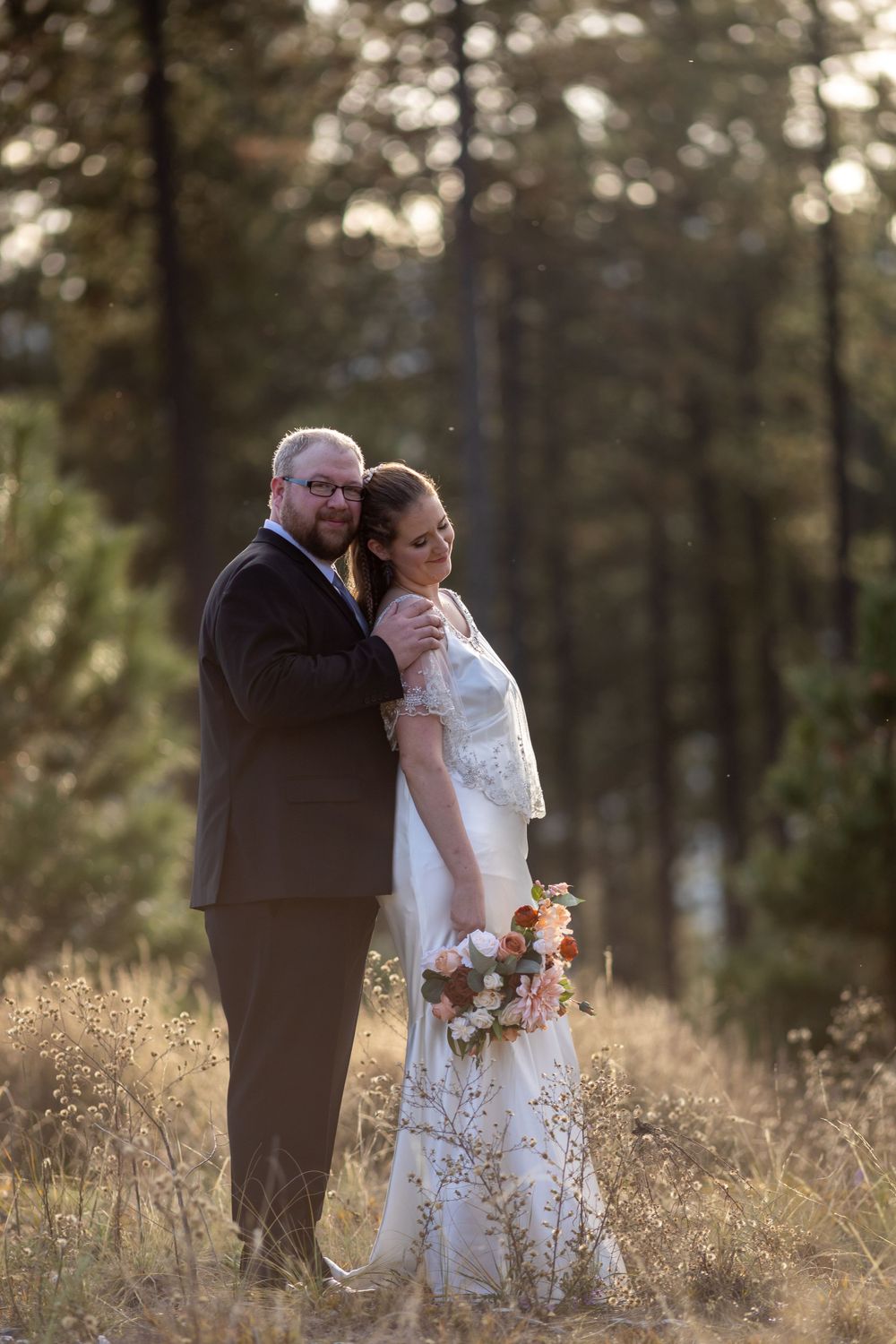 Newlyweds share intimate moment in forest during golden hour.