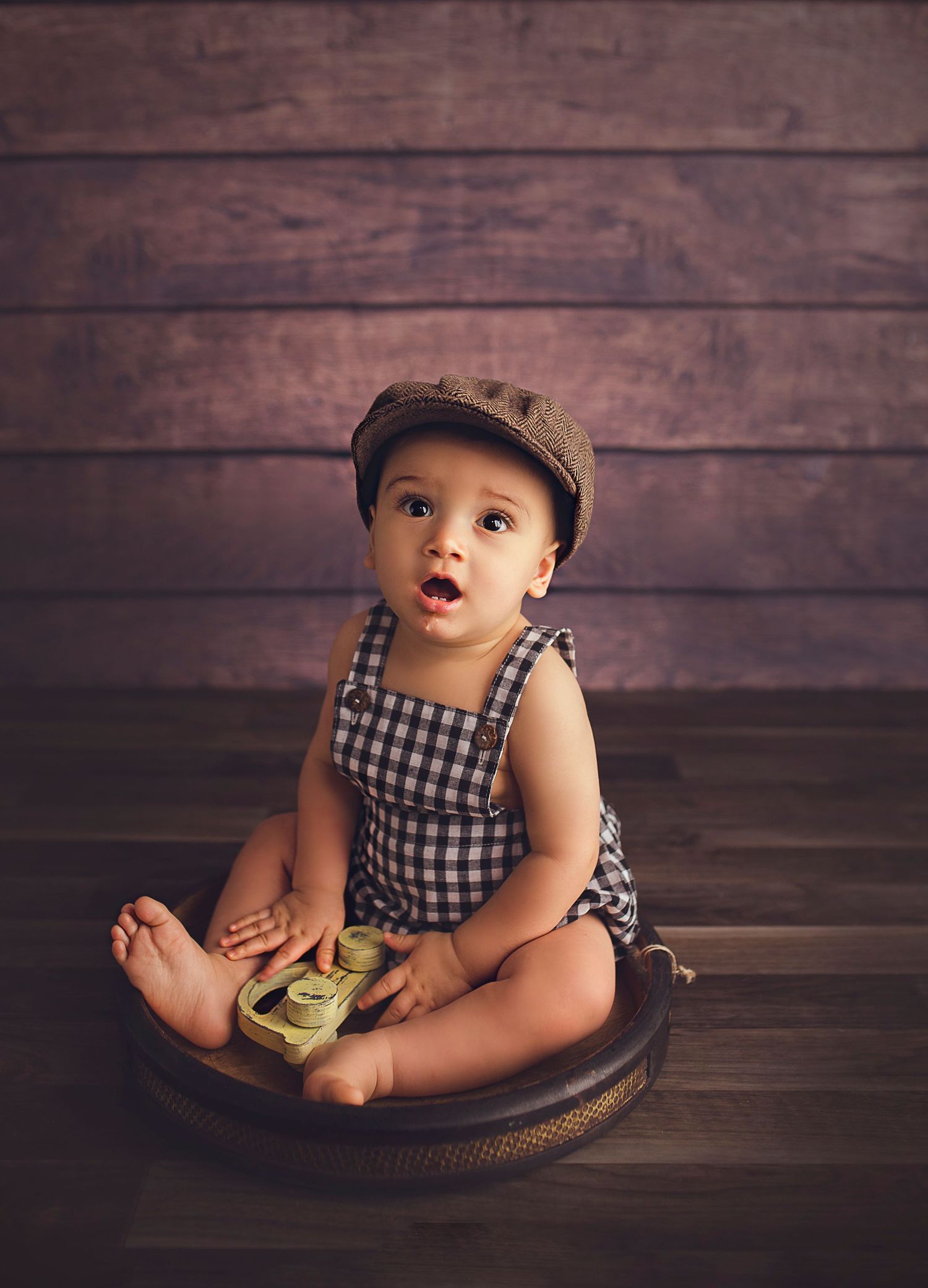 baby boy sitting on wooden bowl with vintage hat