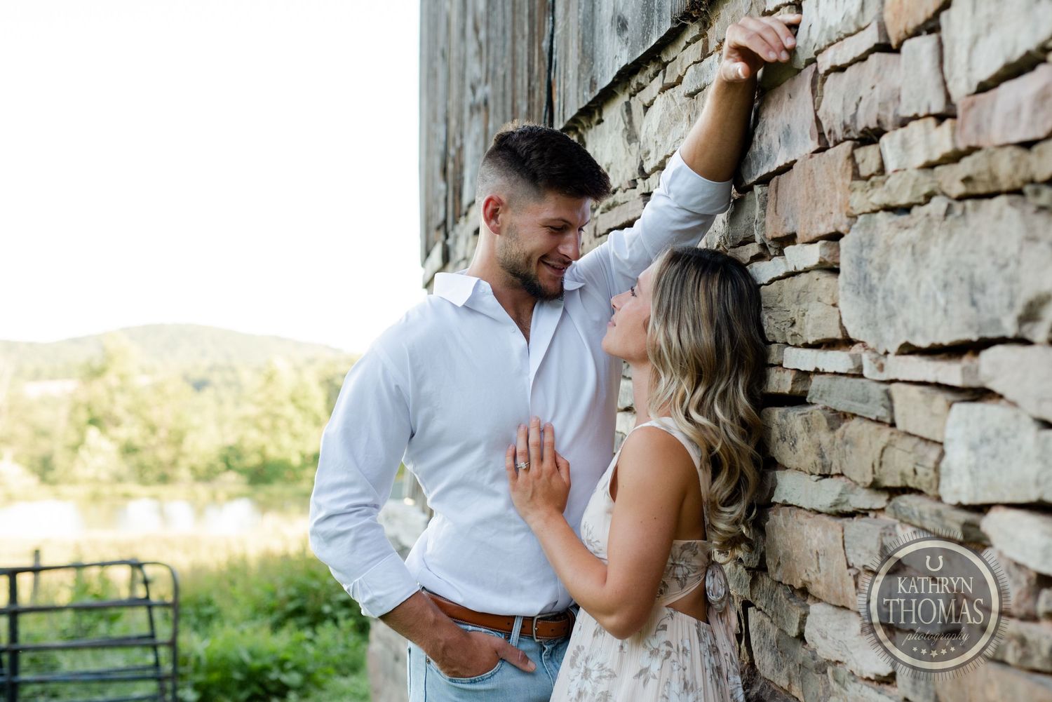 Intimate moment captured between couple against weathered stone wall background.