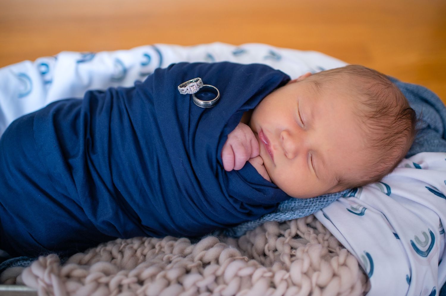 Peaceful newborn baby sleeping while wrapped in navy blue swaddle.
