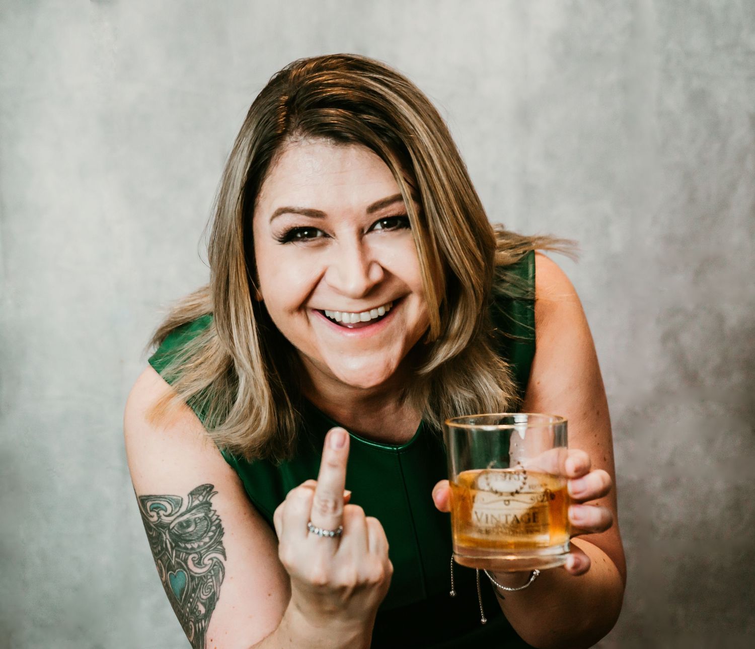 Studio Cake Smash Session in Home Ruskin, FL; Woman flipping off the camera with a glass on bourbon