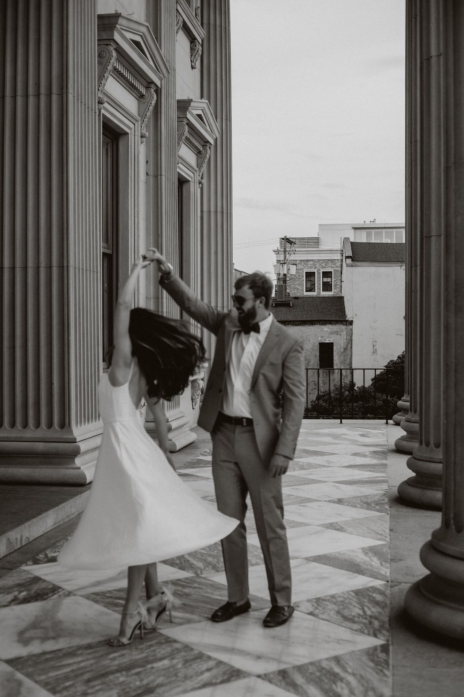 A black and white photo of a man spinning a woman in a dress
