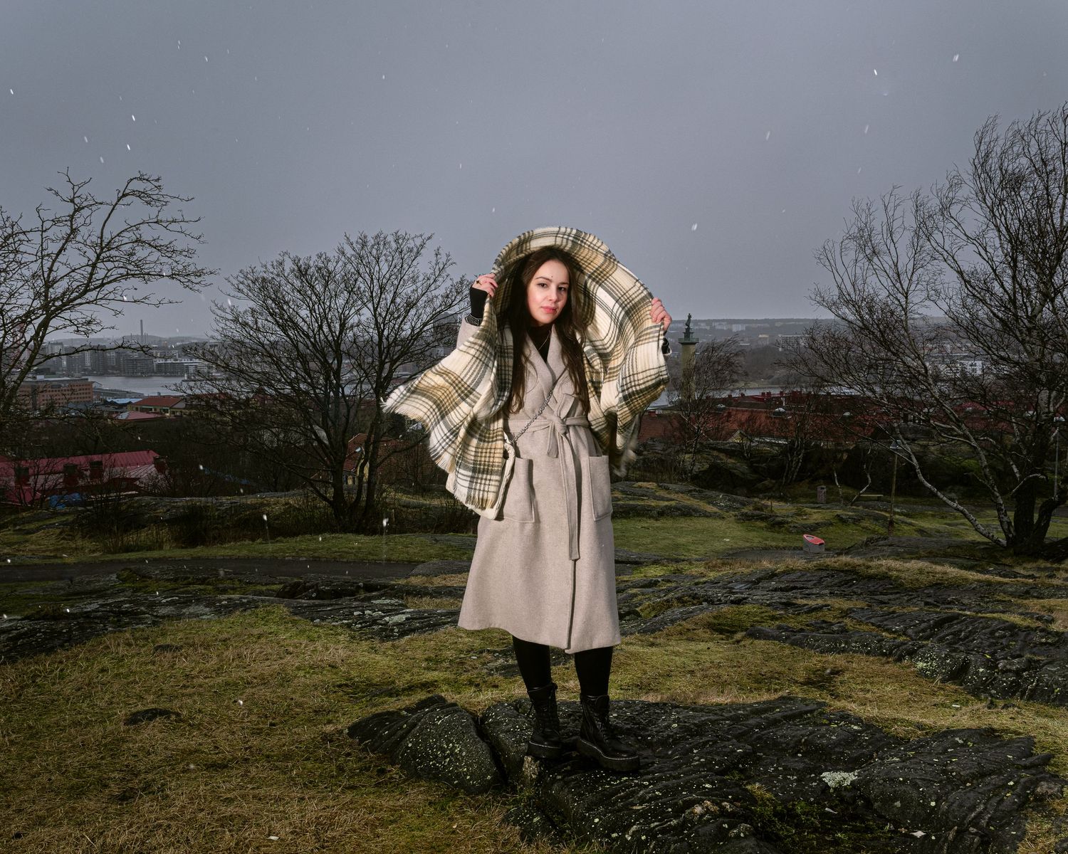 Figure in beige coat walking through windswept winter landscape.
