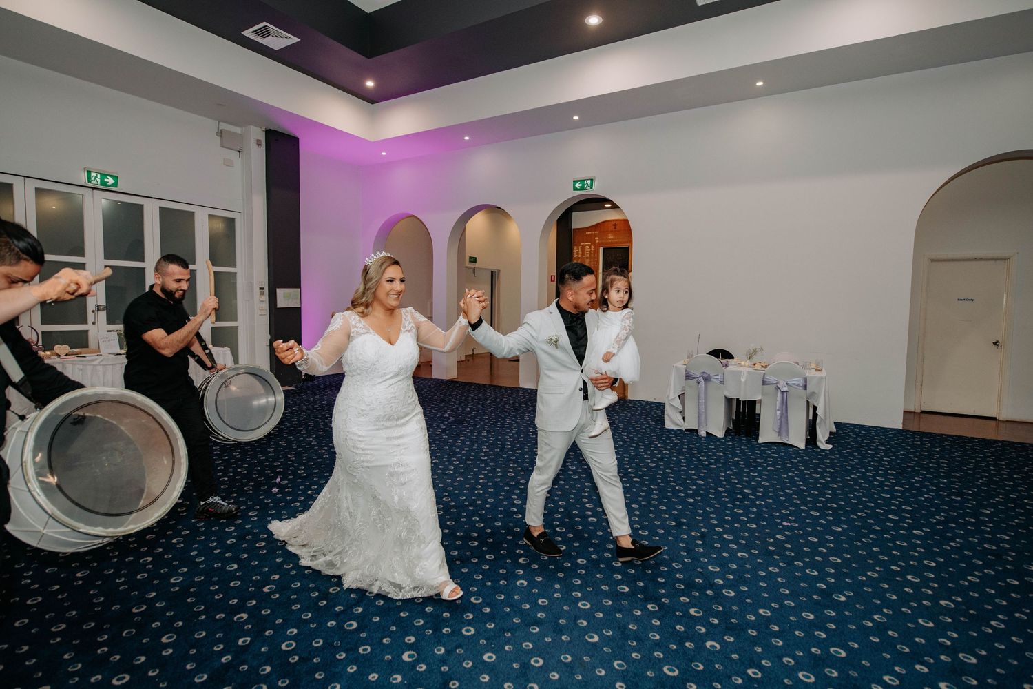 Dancing couple celebrates on the dance floor during their wedding reception in a banquet hall.
