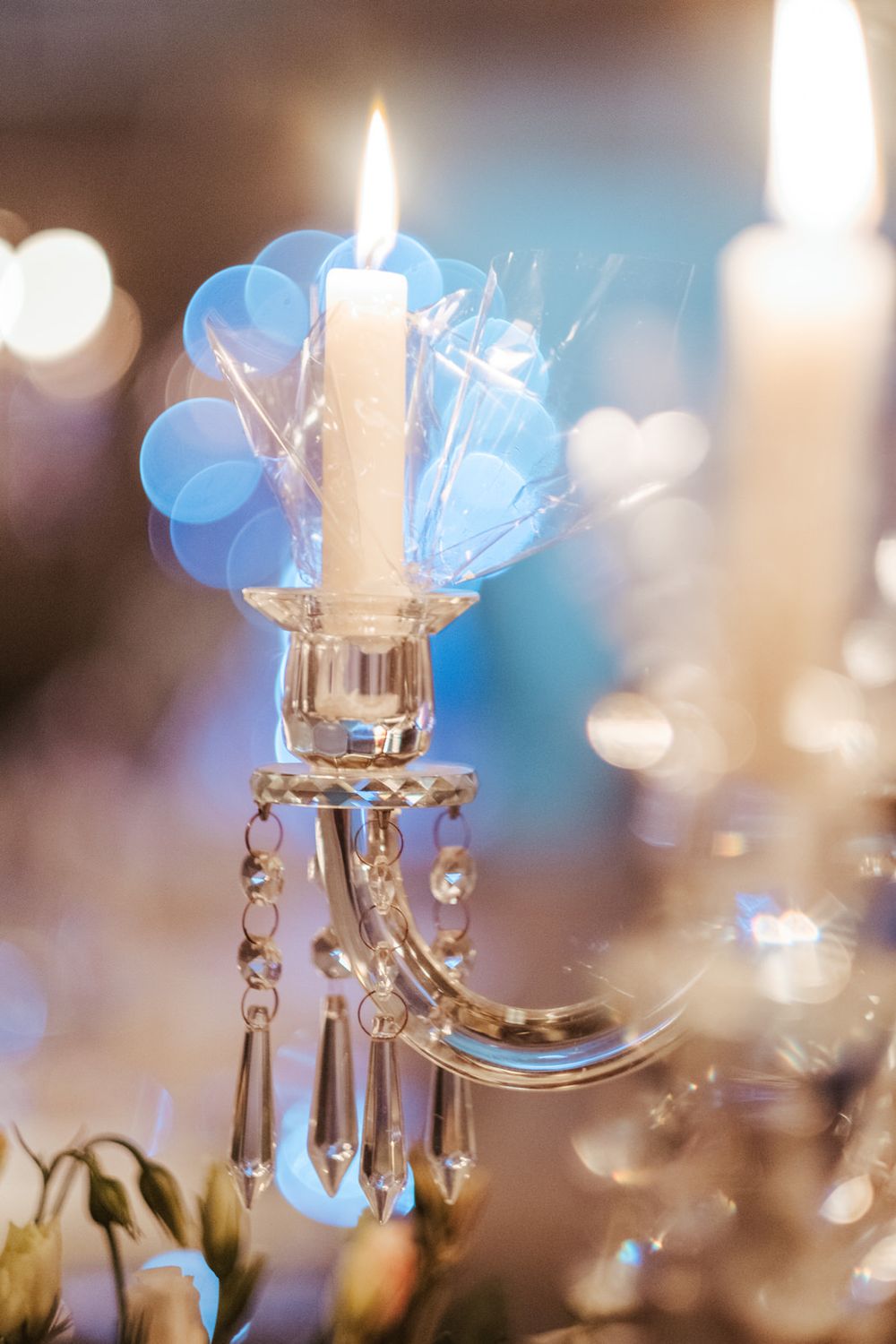 Candelabro de cristal com vela acesa sobre um suave fundo azul desfocado.