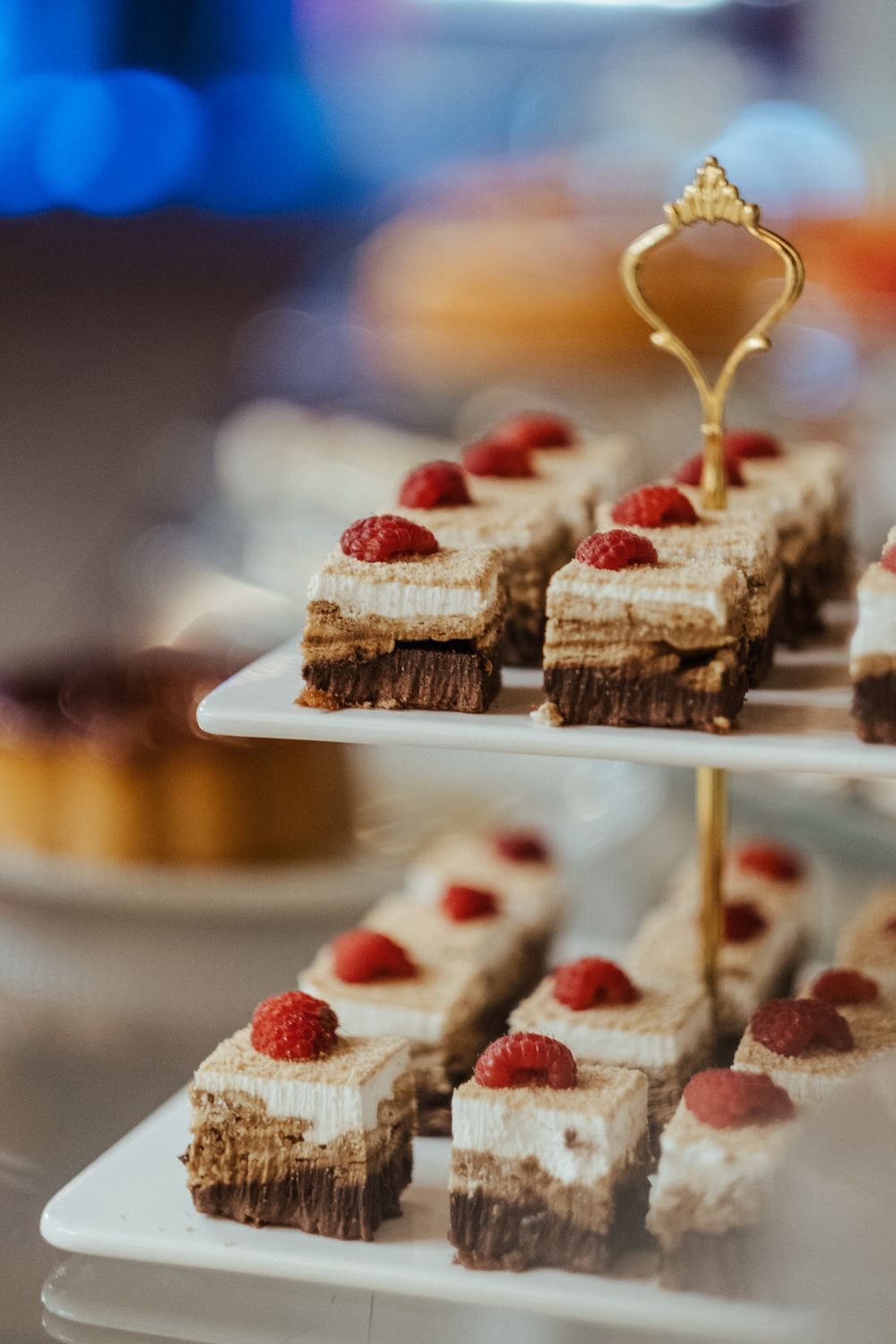Elegante suporte de sobremesas de vários andares que exibe mini bolos de chocolate com framboesa.