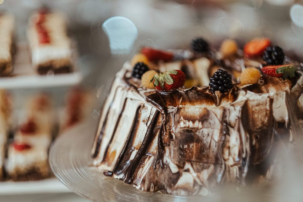 Pormenor de sobremesas gourmet de chocolate cobertas com frutos vermelhos frescos em exposição.