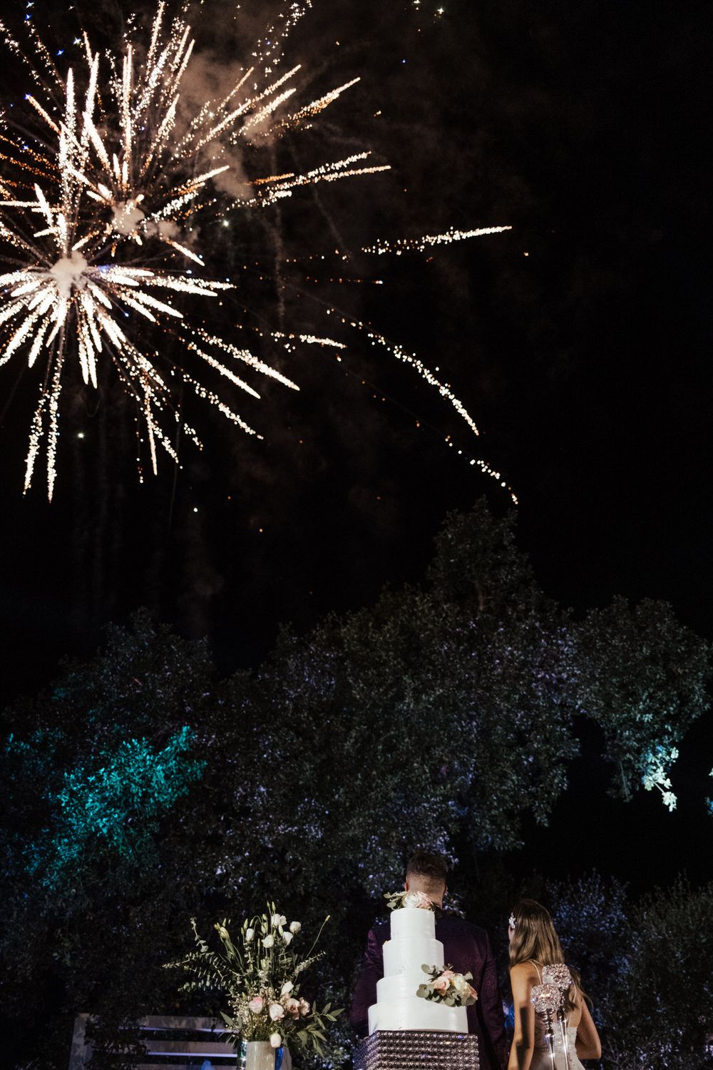 Espetáculo de fogo de artifício a iluminar o céu noturno durante uma festa de casamento.