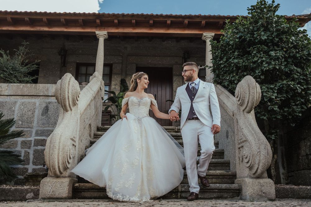 Retratos de casamento tirados num edifício rústico de pedra com estátuas decorativas de pedra.