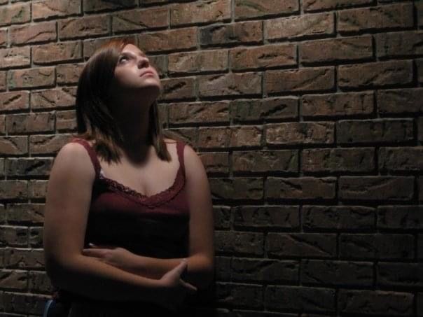 Artistic portrait series against textured brick wall in dramatic lighting.