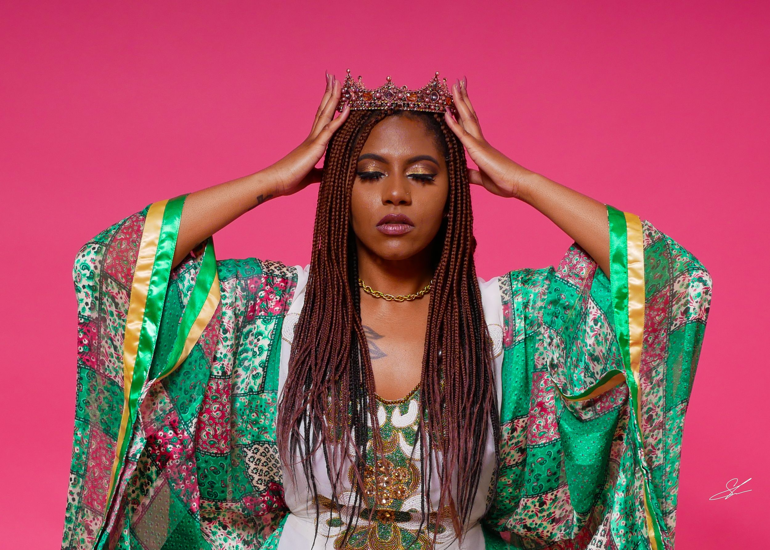 Regal pose in emerald green patterned kimono against bright pink background.