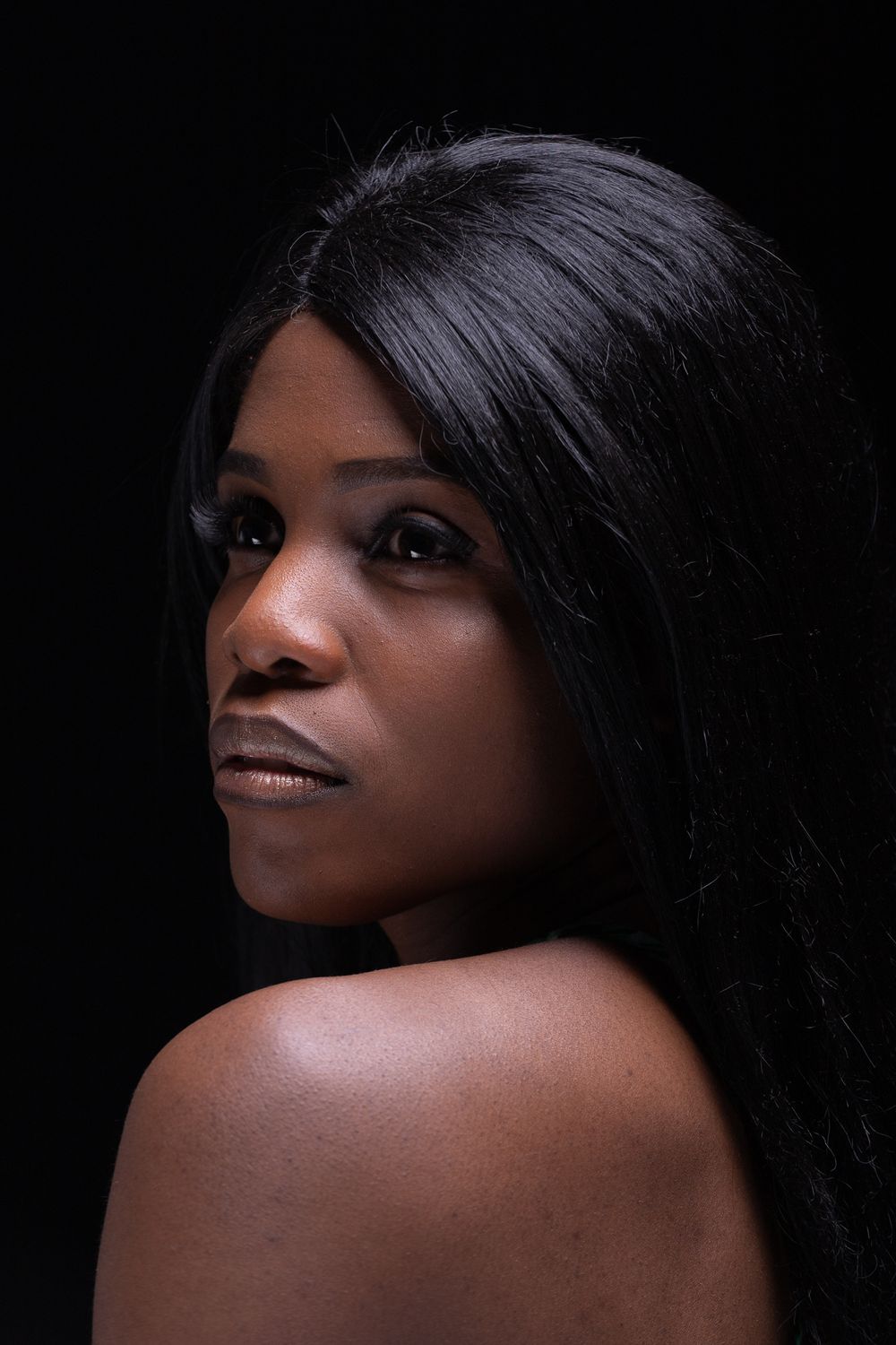 Artistic black and white portrait against dark background highlighting dramatic lighting and deep shadows.