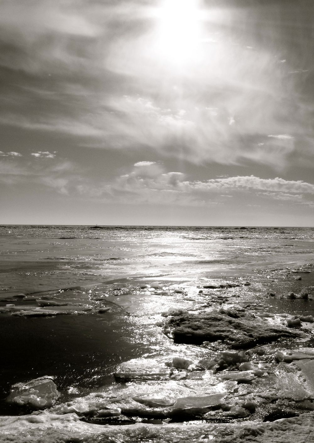Dramatic black and white seascape with sunlight reflecting off rocky ocean waves, 35mm film.