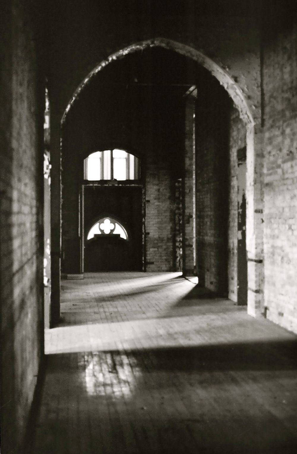 Black and white architectural photo of arched hallway with dramatic lighting and shadows at Alma College, London Ontario..