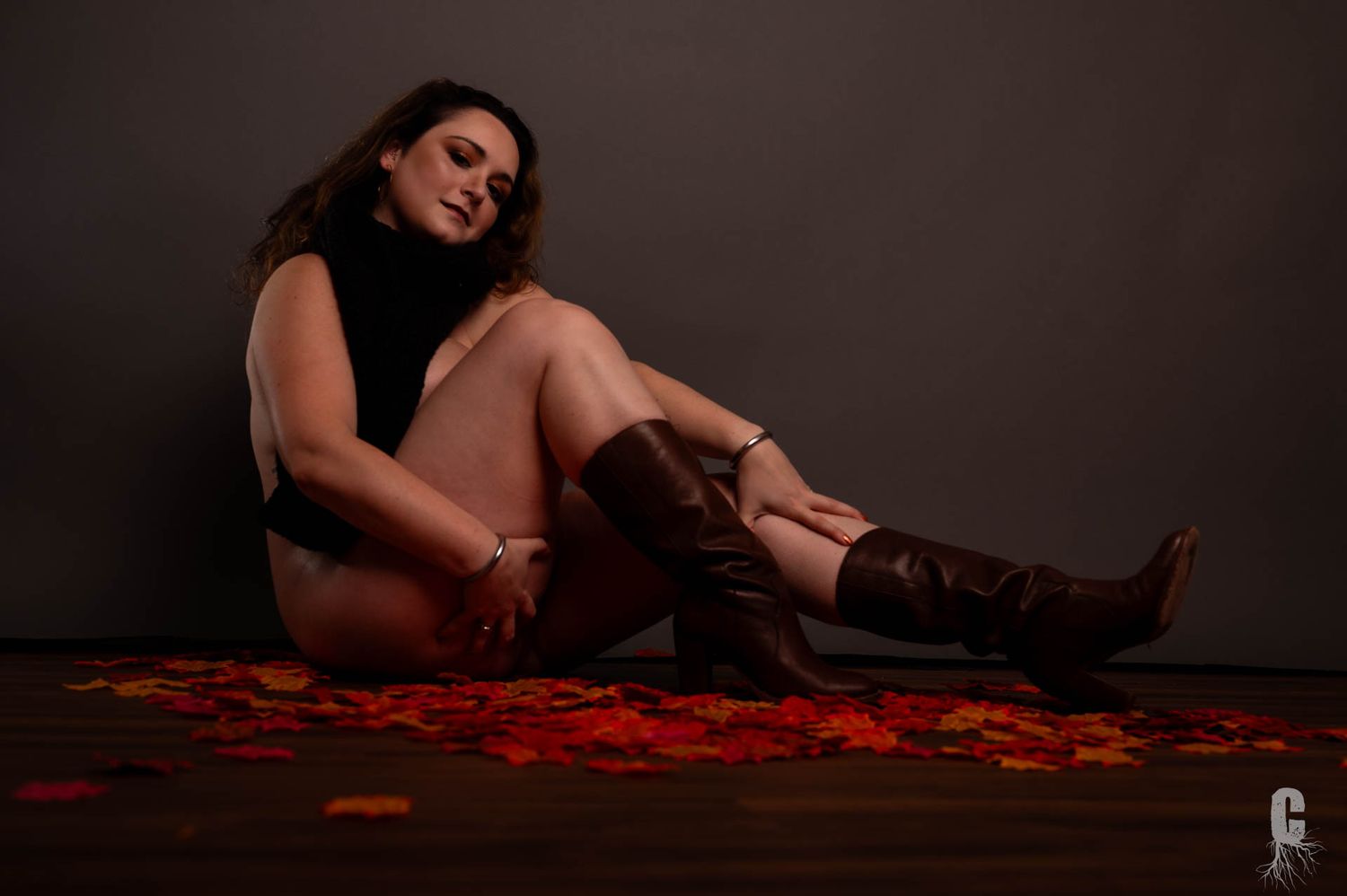 A boudoir model in knee high leather boots in a Fall themed set
