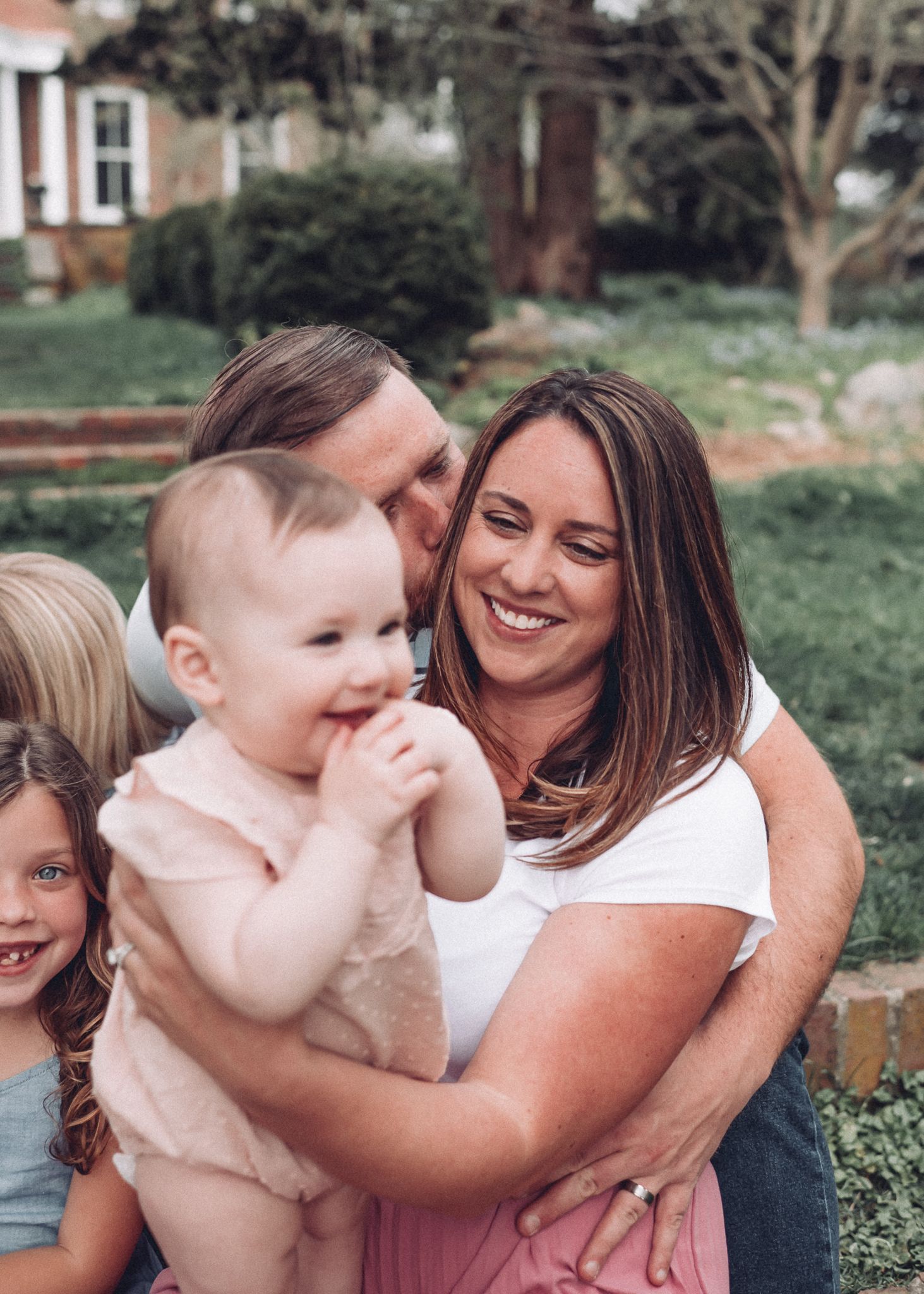 A candid moment of joy shared between family members in a backyard garden setting.