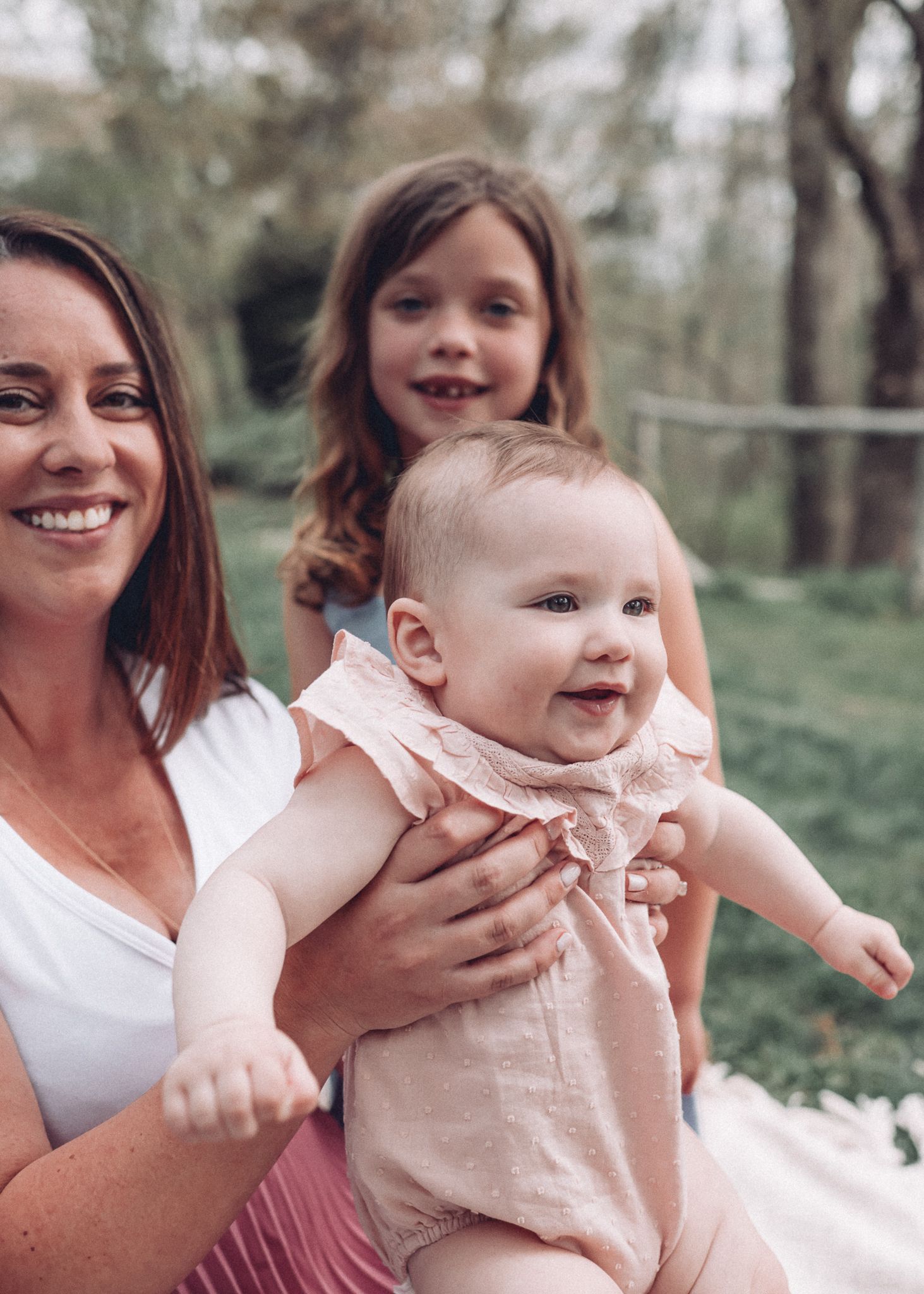 A joyful outdoor family portrait with matching outfits and natural garden backdrop.