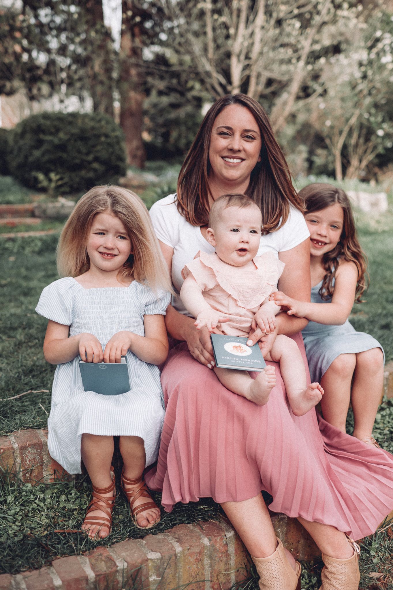 Family sitting on brick steps in coordinated outfits during springtime photoshoot.